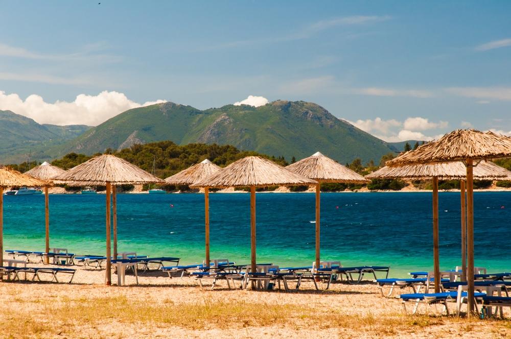 Pokojná pláž s ležadlami a slamenými slnečníkmi na ostrove Meganisi v Grécku