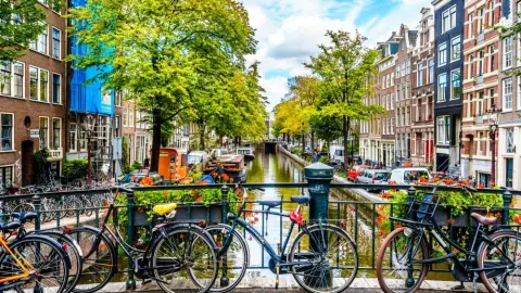 Most s bicyklami ponad kanál v Amsterdame s typickou architektúrou a zeleňou.