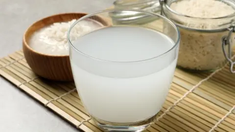Pohár čerstvej ryžovej vody pripravený na pitie, vedľa misky s bielou ryžou