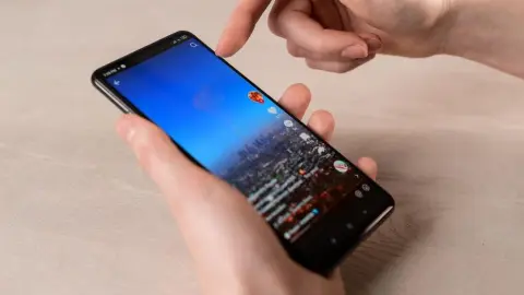 Osoba drží v ruke mobilný telefón a prechádza videá na TikToku.