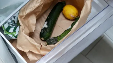 Mierne zaplesnené uhorky a citrón v papierovom vrecku v zásuvke chladničky