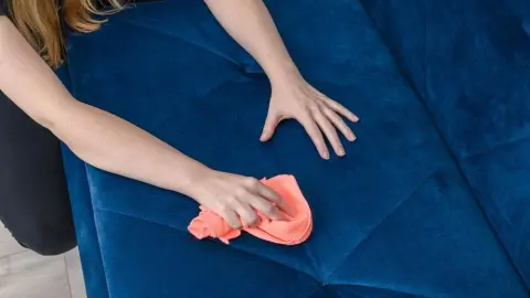 Čistenie zamatovej pohovky ručne oranžovou handričkou
