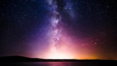 Mliečna cesta žiariaca na nočnej oblohe nad horizontom v čase astronomického úkazu
