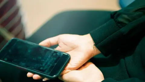 Špinavý displej smartfónu s viditeľnými odtlačkami prstov v rukách ženy