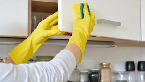 Žena čistí skrinky v kuchyni pomocou octového roztoku v spreji
