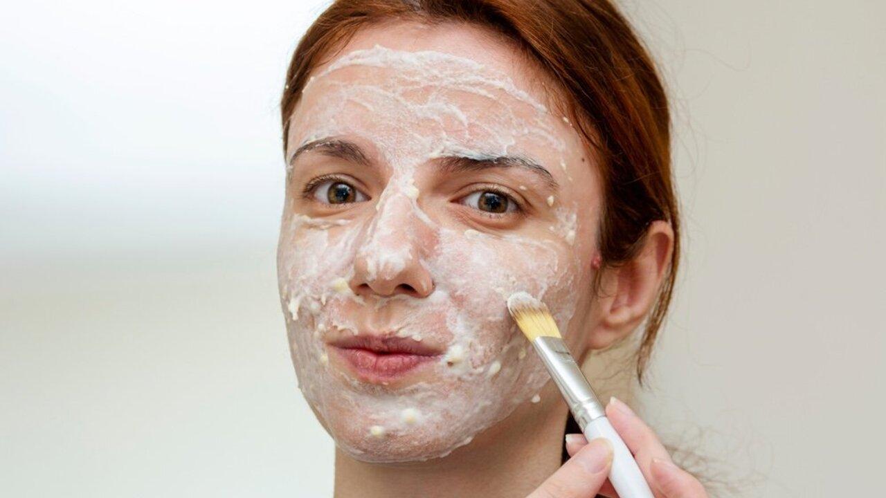 Žena nanáša na tvár domácu banánovú masku s olivovým olejom.