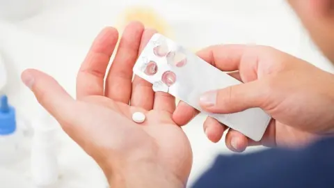 Človek drží v ruke antibiotikum a blister s tabletkami