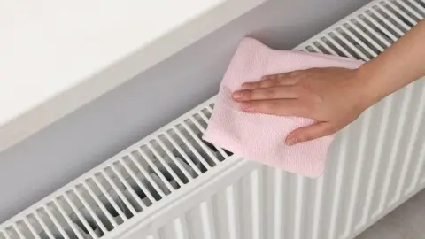 Čistenie radiátora handričkou z mikrofibry pred vykurovacou sezónou