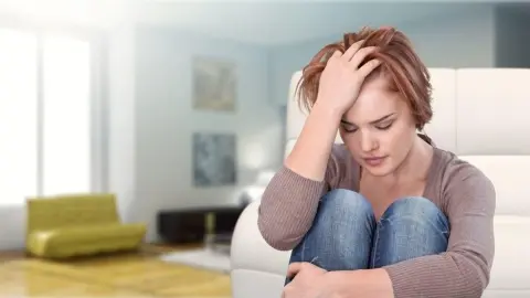 Žena sediaca na zemi so sklonenou hlavou prežíva stres a únavu.