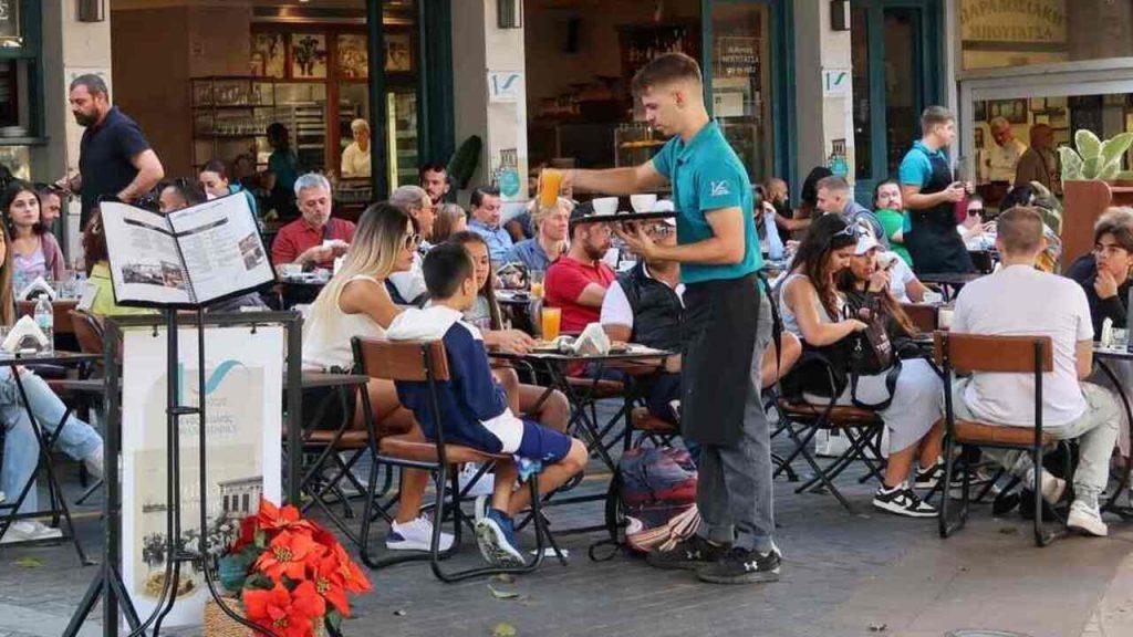 Ľudia si užívajú kávu a jedlo na terase kaviarne v centre Heraklionu na Kréte počas slnečného jesenného dňa