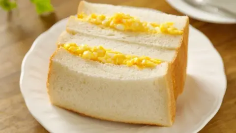 Tradičný japonský vajíčkový sendvič Tamago sando na bielom tanieri.