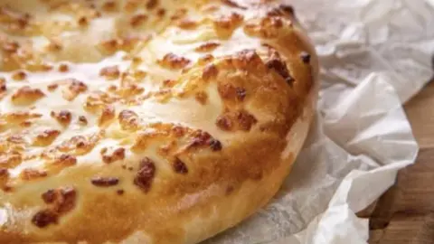 Detail zlatistého gruzínskeho chleba chacapuri s roztopeným syrom na papieri