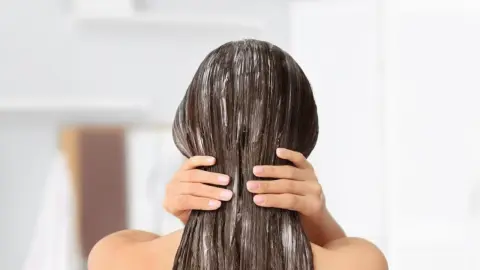 Žena si doma nanáša prírodnú masku na vlasy