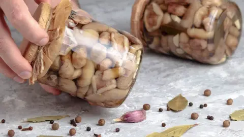 Pohár s nakladanými hubami v octovej zálievke s bylinkami a korením