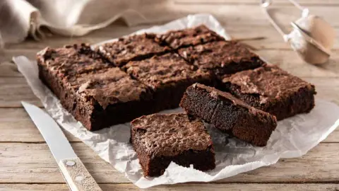 Čerstvo upečené čokoládové brownies nakrájané na kúsky, s lesklým popraskaným povrchom a vláčnym vnútrom.