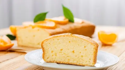 Vláčny pomarančový koláč posypaný práškovým cukrom na tanieri
