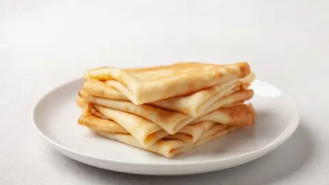Nadýchané a zlatisté palacinky z kefírového cesta poskladané na bielom tanieri.