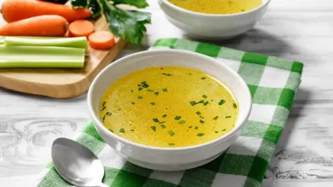 Miska domáceho vývaru s petržlenom, položená na zelenej kockovanej utierke