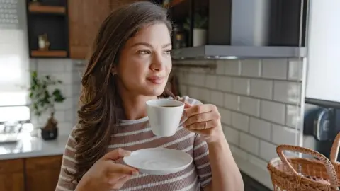 Žena si doma vychutnáva šálku kávy pri rannom svetle
