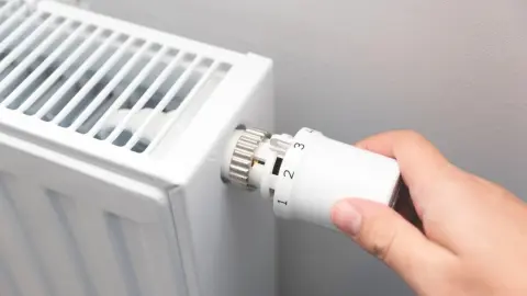 Detail termostatu na radiátore s číselnými stupňami teploty.