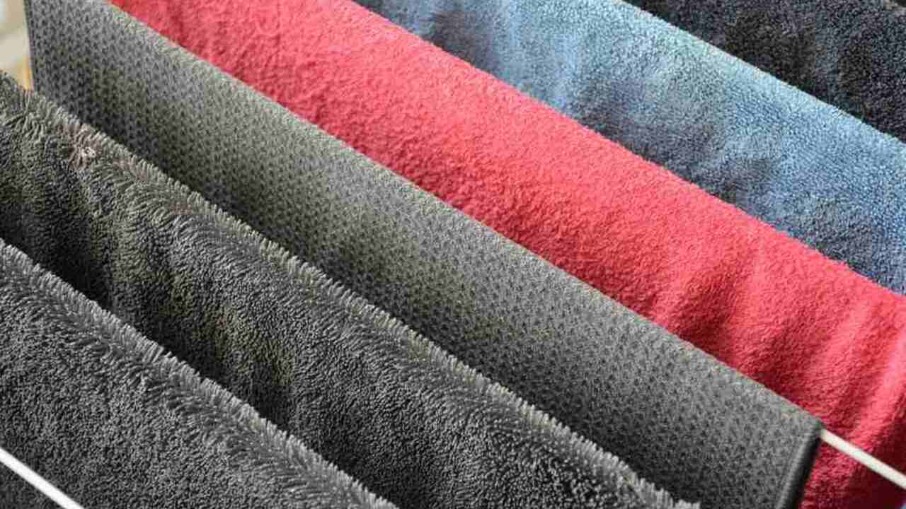 Farebné uteráky rozložené na sušiaku, ktoré sa sušia na vzduchu v interiéri.