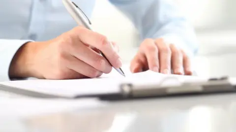 Ruka zapisuje odpovede do testu inteligencie na papier.