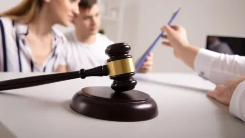 Sudcovské kladivko na stole počas konzultácie o dedičstve s mladým párom