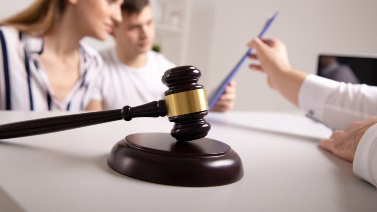 Sudcovské kladivko na stole počas konzultácie o dedičstve s mladým párom