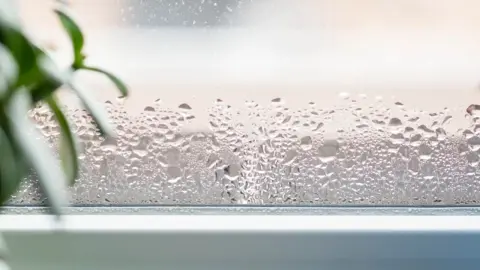 Orosené okno so stekajúcimi kvapkami vody počas zimy.