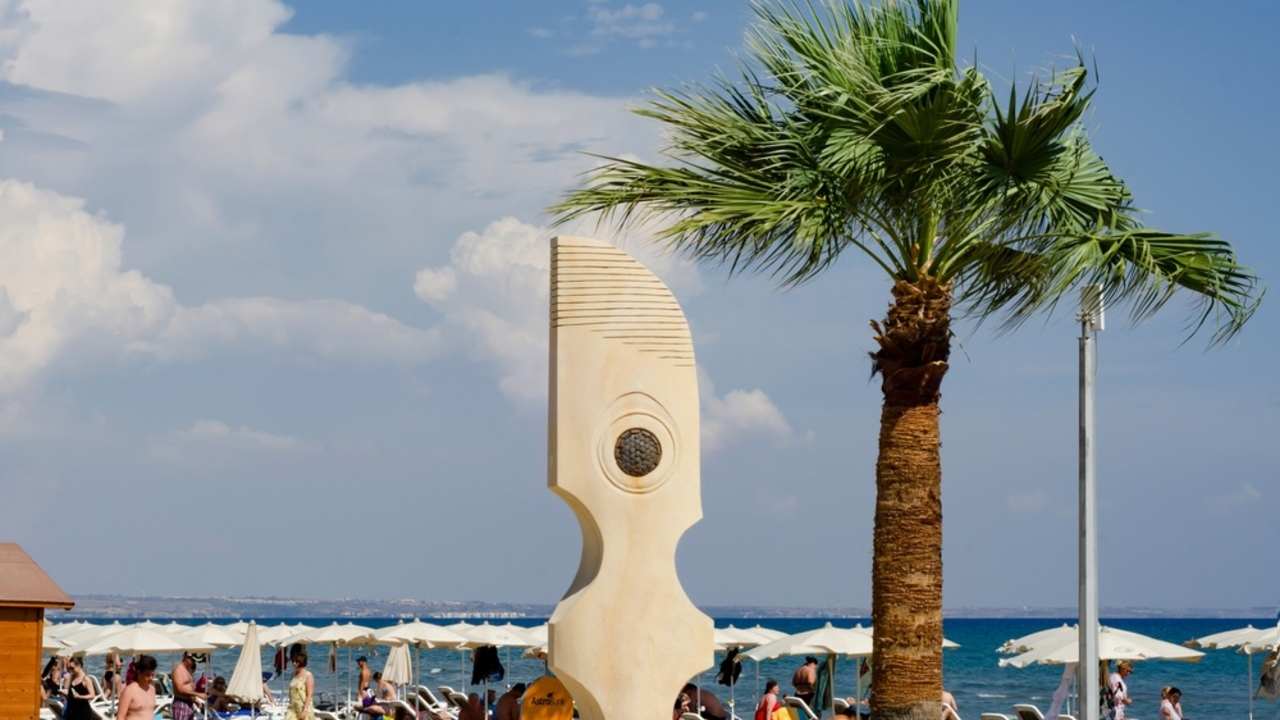 Jesenný deň na pláži v Larnake s teplým morom a prázdnymi ležadlami.