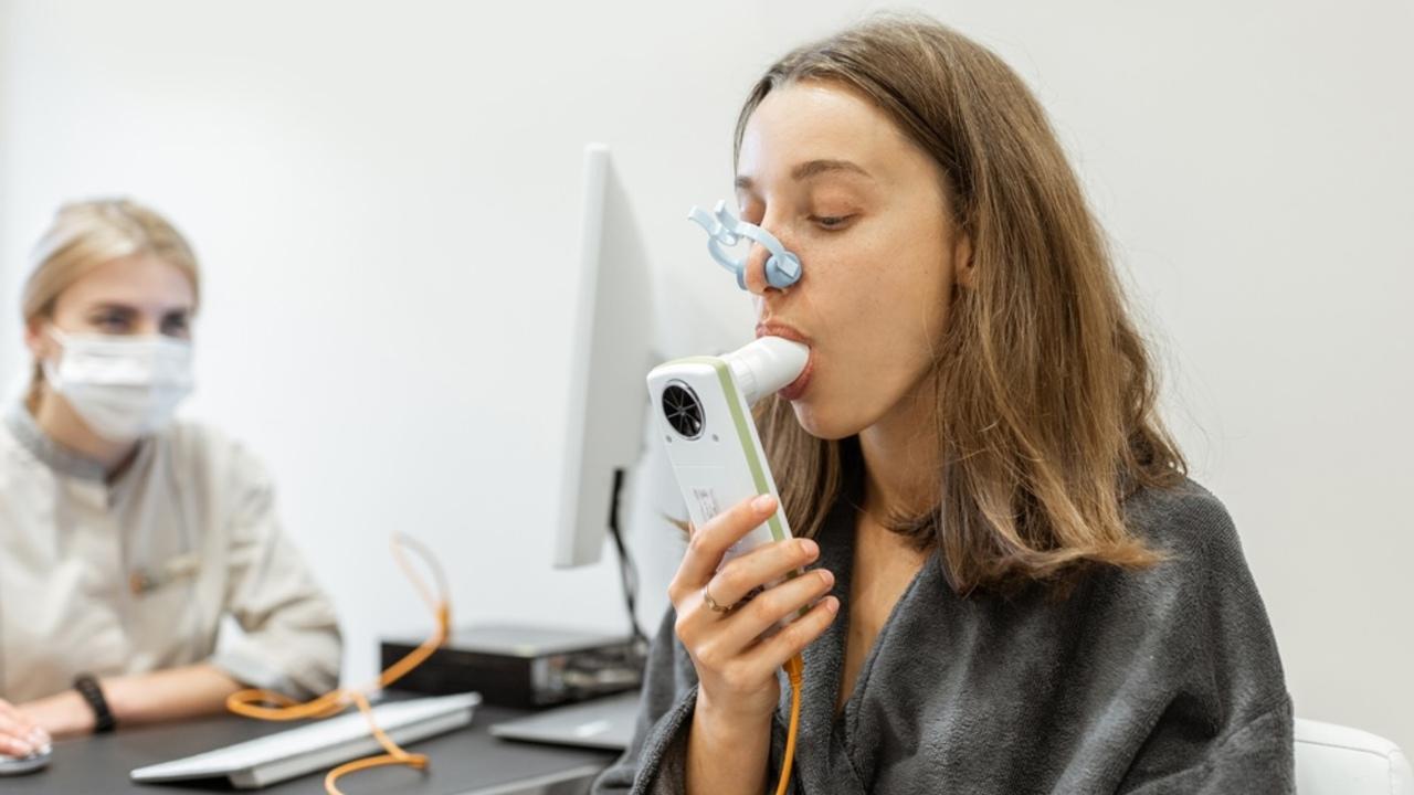Mlad&aacute; žena s lek&aacute;rom počas spirografick&eacute;ho testu, meranie d&yacute;chac&iacute;ch pohybov spirometrom v zdravotn&iacute;ckom k&uacute;peľnom sal&oacute;ne