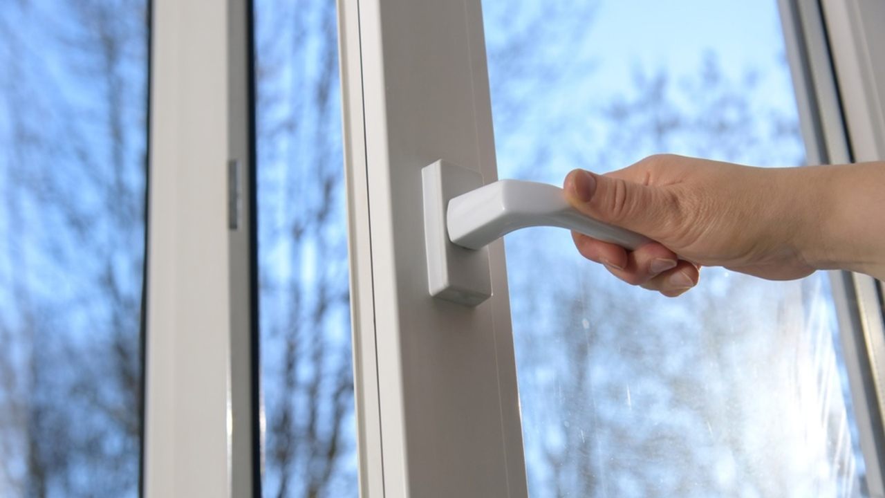 Ruka otvára okno počas zimy, aby do spálne mohol prúdiť čerstvý vzduch.