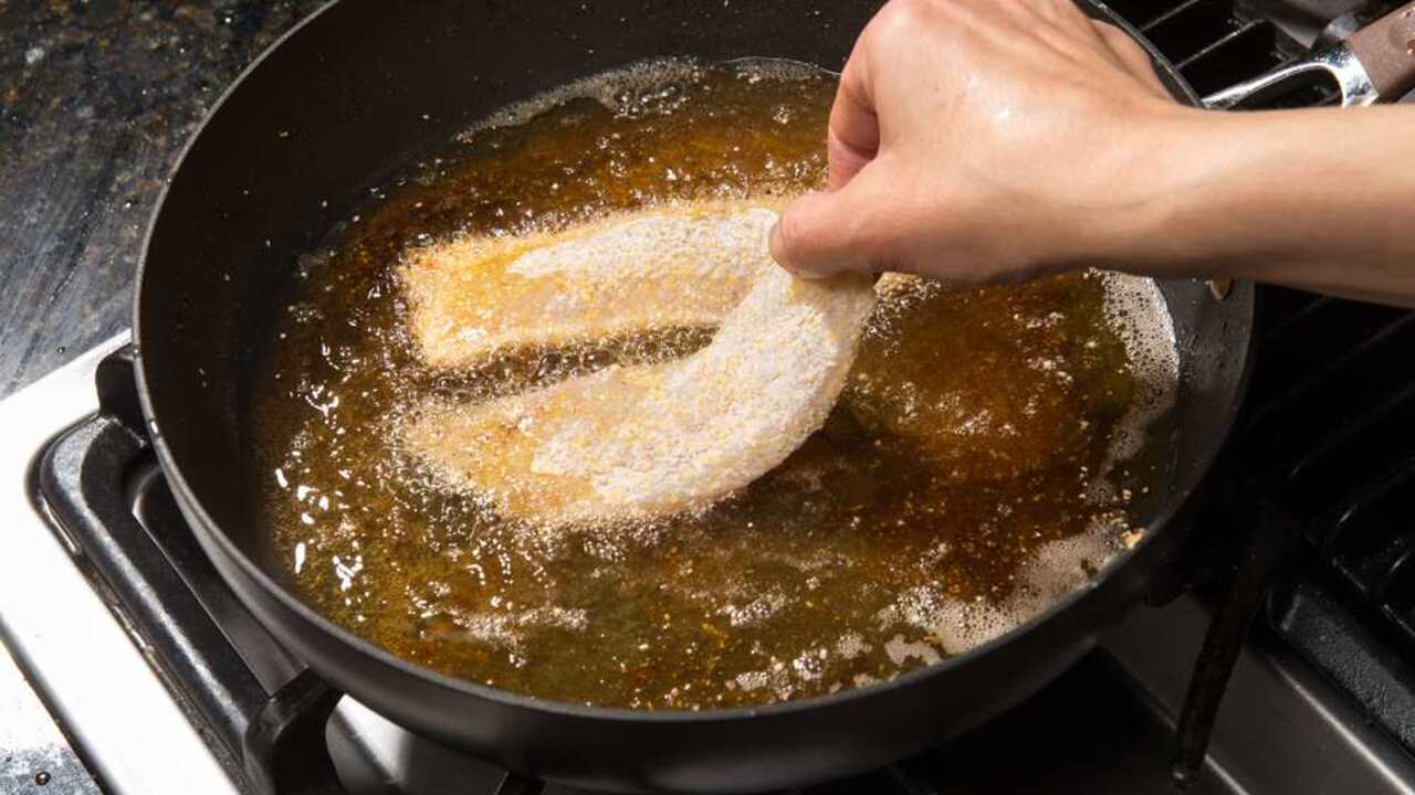 Vyprážanie obaľovaného rybieho filé na panvici v horúcom oleji