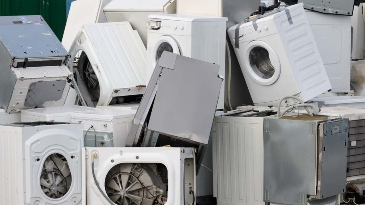 Hromada vyradených práčok a domácich spotrebičov pripravených na spracovanie elektroodpadu.