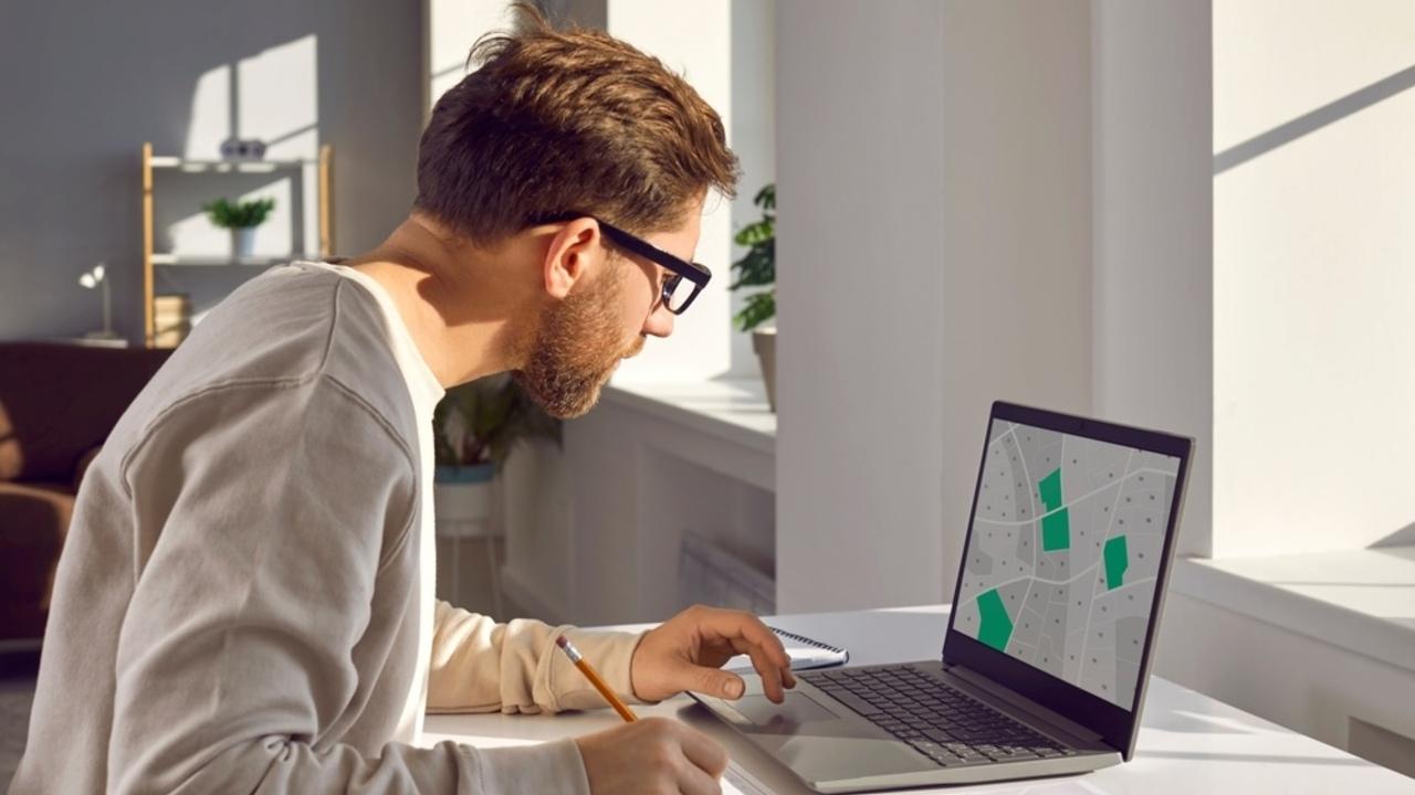 Dokumenty a katastrálna mapa s označenými parcelami, symbolizujúce zmeny v prístupe k údajom.