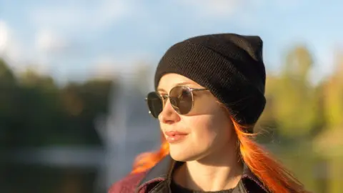 Žena sa prechádza v jesennom parku počas slnečného dňa.