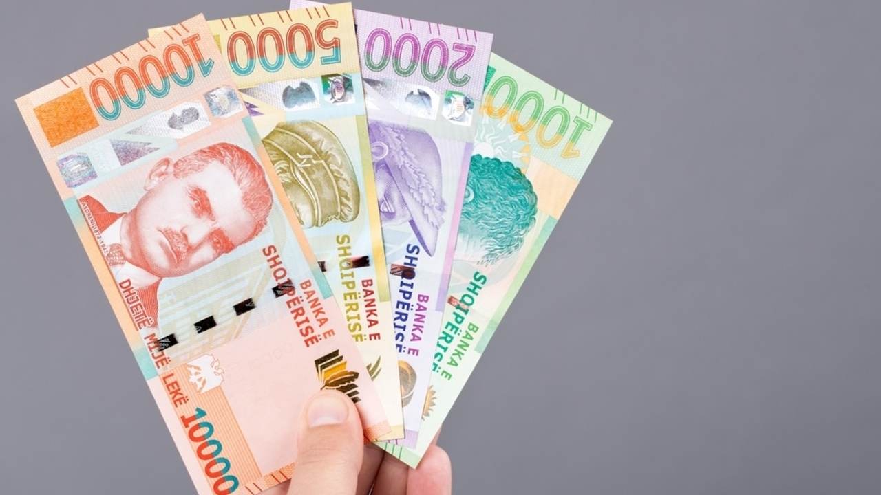 Albánska mena – lek v ruke na sivom pozadí