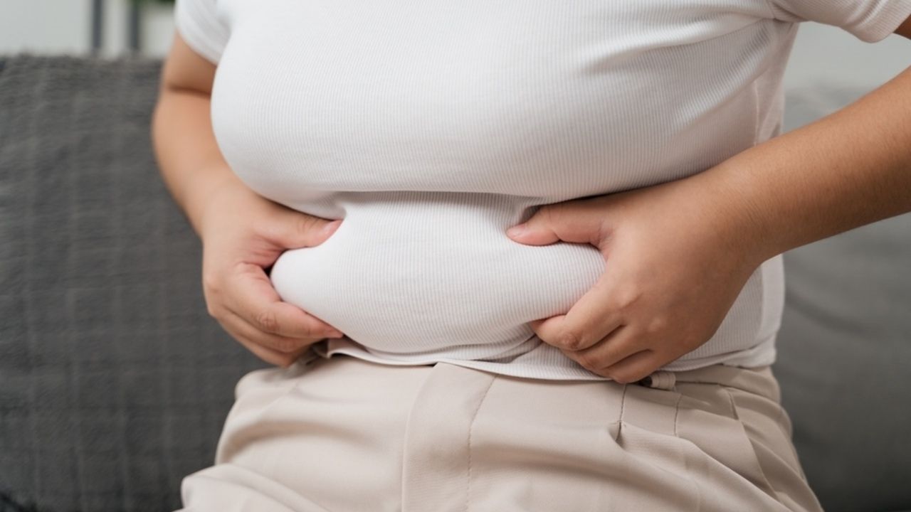 Detail brucha, na ktorom si žena jemne drží pneumatiku tuku, symbolizujúci rozdiel medzi podkožným a vnútorným tukom.