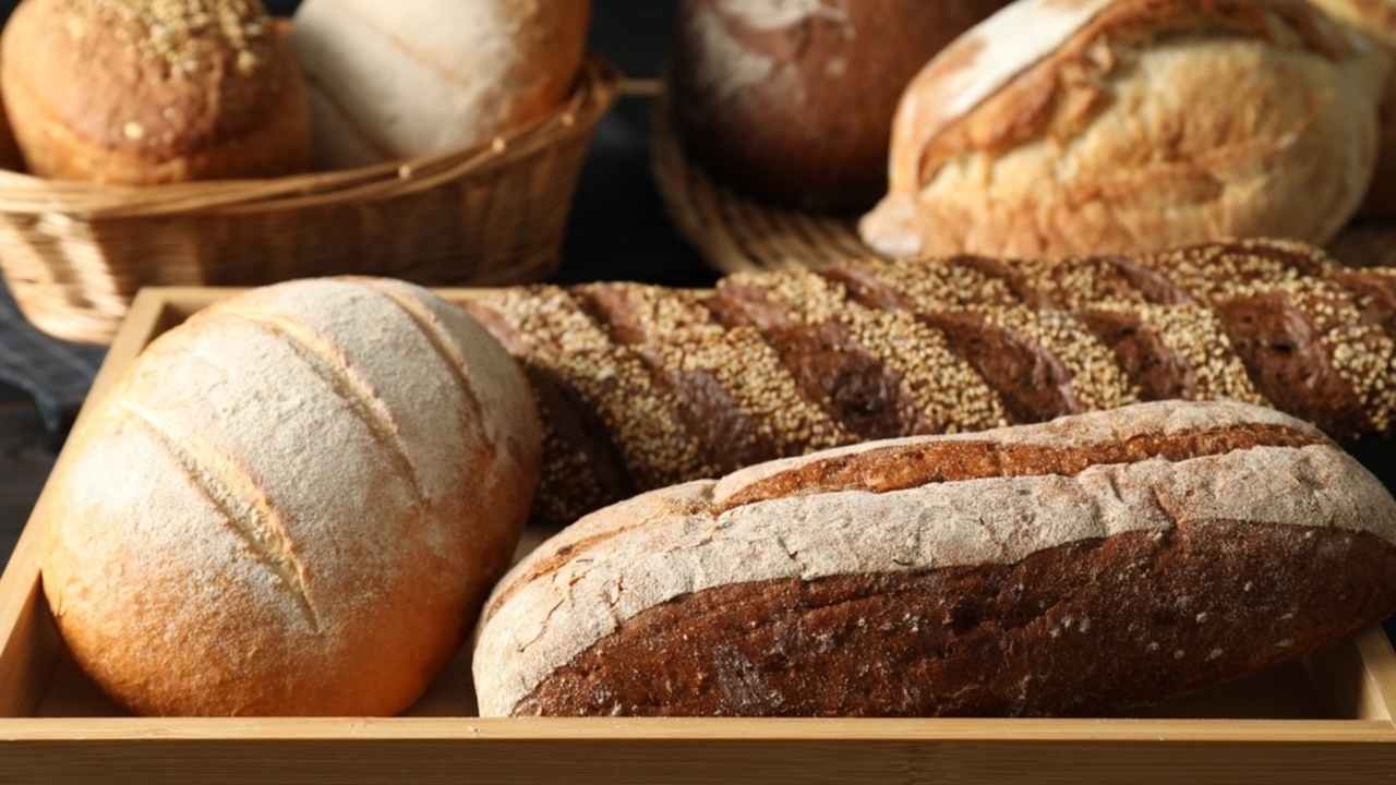 Rôzne druhy čerstvého chleba uložené v košíkoch a na drevenom podnose.