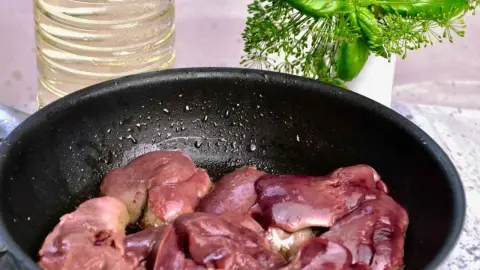 Pečeň s cibuľou na panvici počas vyprážania