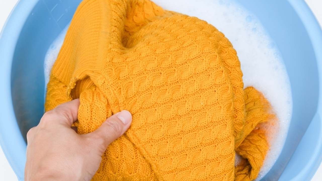 Ručné pranie vlneného svetra v studenej vode v miske.