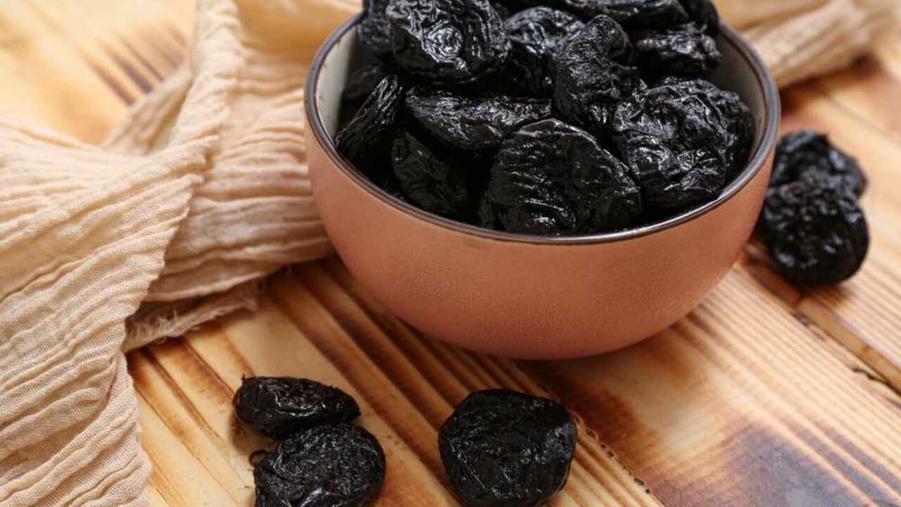 Sušené slivky v miske položené na drevenom stole