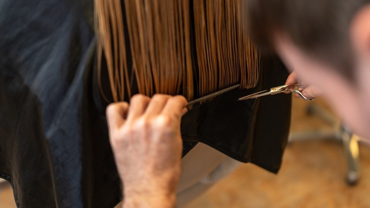 Kaderník upravuje žene tupý strih s presnou rovnou líniou.