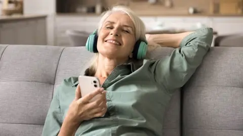 Žena s bezdrôtovými slúchadlami počúva hudbu a usmieva sa