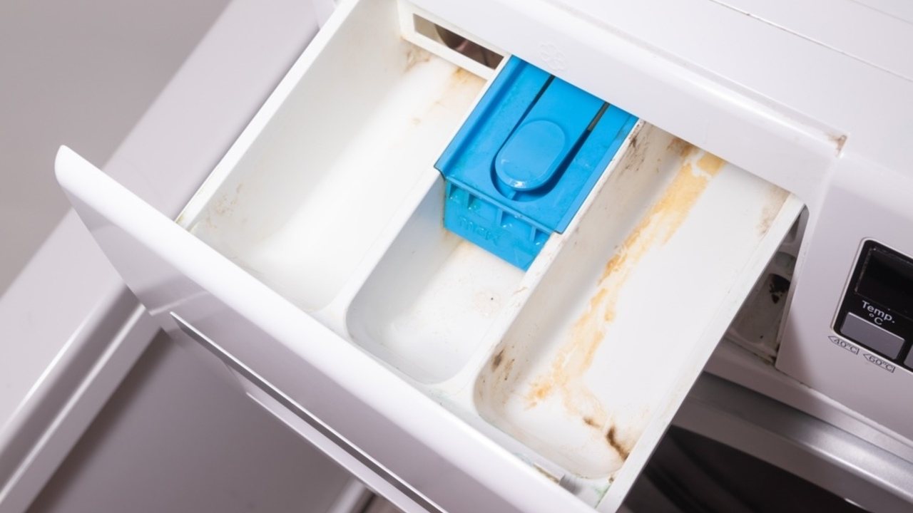 Zásuvka práčky so zvyškami prášku pripravená na čistenie