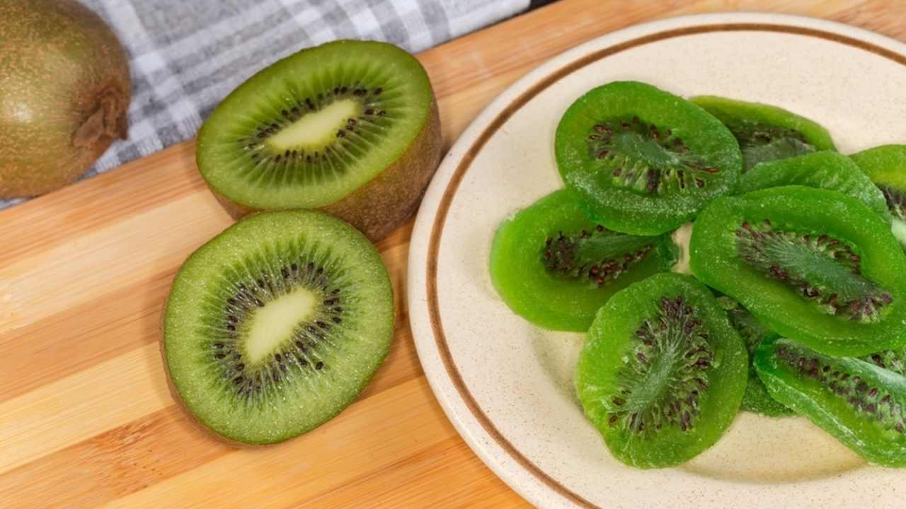 Čerstvé kiwi nakrájané na polovicu na tanieri a drevenom stole.