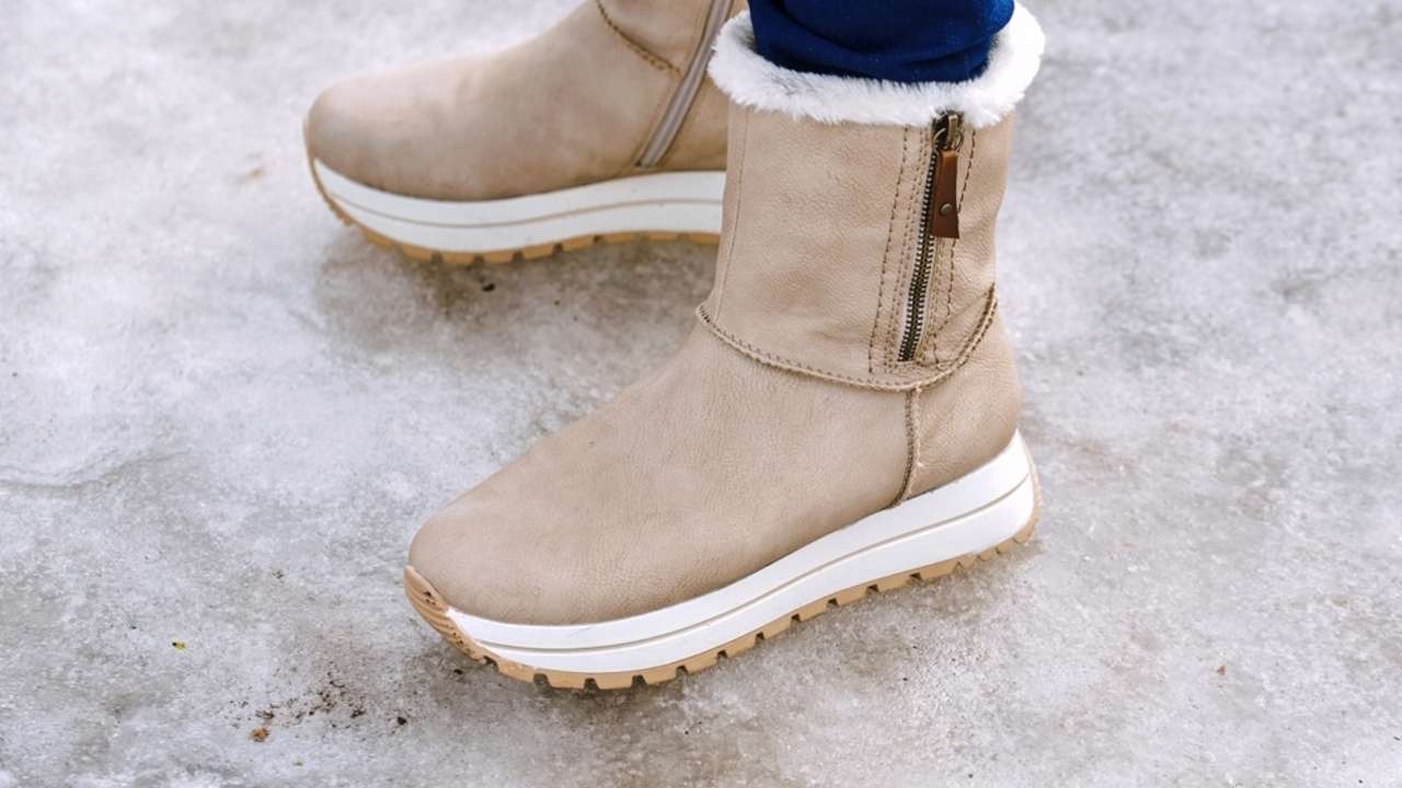 Zimné čižmy na zľadovatenom chodníku, detail podrážky na hladkom ľade.