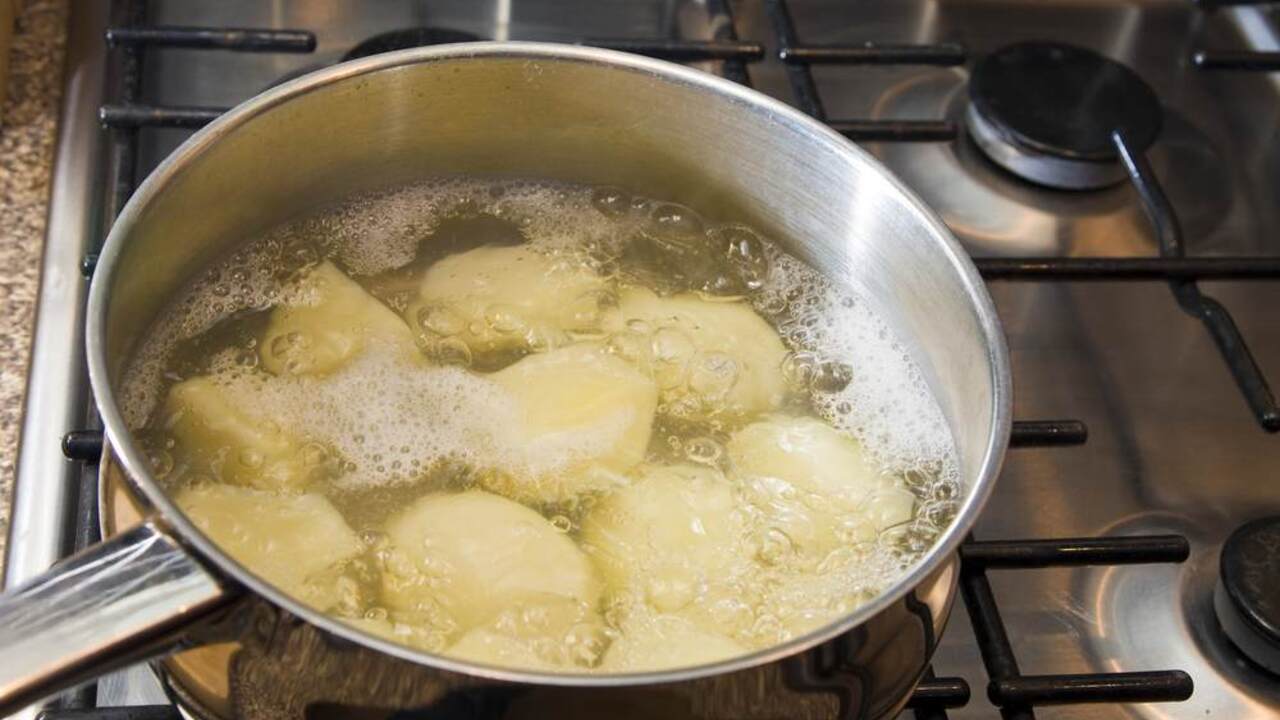 Zemiaky sa varia v hrnci s vodou na plynovom sporáku, voda jemne bublá.