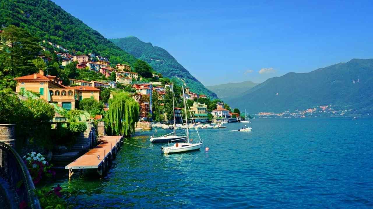 Pohľad na pobrežie mesta Moltrasio pri jazere Como obklopené horami a farebnými vilami