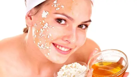 Žena nanáša na tvár domácu tvarohovú masku s medom a olejom.